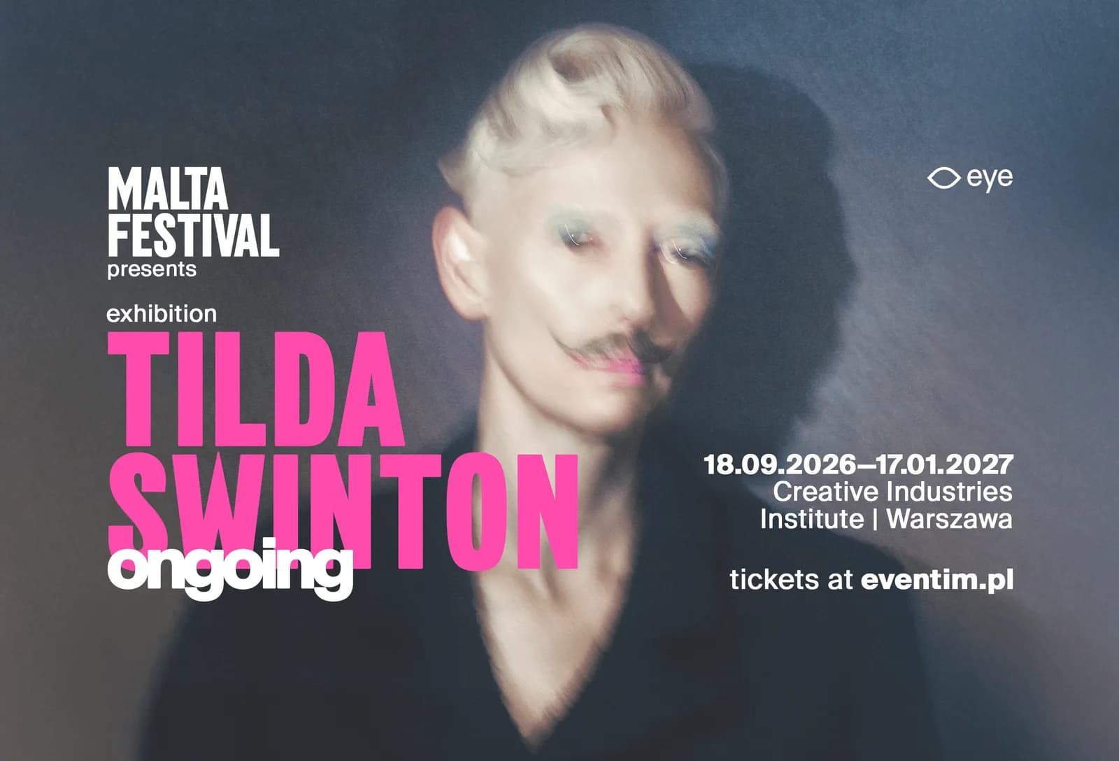 Tilda Swinton, with blonde hair styled upwards, a faint mustache, and light blue eyeshadow, looks directly at the viewer in a soft-focus image, overlaid with text about the Malta Festival and an exhibition of her work.